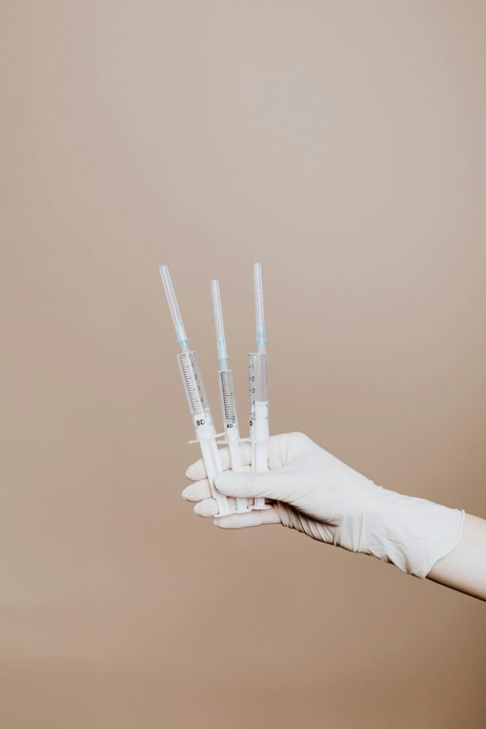 Home Close-up of gloved hand holding sterile syringes, symbolizing healthcare and vaccination.