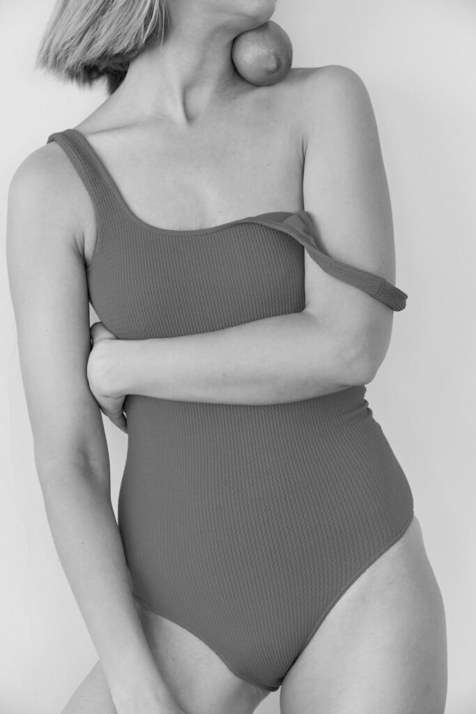 Services Black and white close-up of a woman in a swimsuit with an orange.
